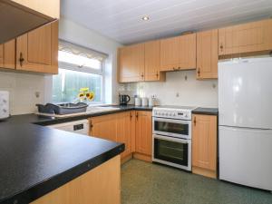 Una cocina con gabinetes de madera y un refrigerador blanco. en Blue Skies Cottage, en Arbroath