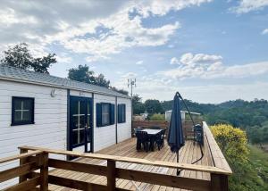 une terrasse en bois avec une table et un parasol dans l'établissement Joli Chalet avec grande terrasse et accès piscine, à Rocbaron