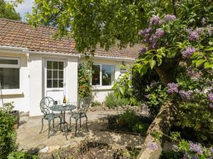 ein Cottage mit einem Tisch und Stühlen im Garten in der Unterkunft Long Batch Cottage in Shepton Mallet