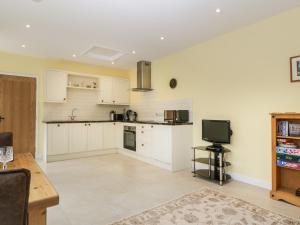 uma cozinha com armários brancos e uma televisão em Long Batch Cottage em Shepton Mallet
