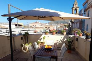 una mesa y sillas bajo una sombrilla en el balcón en [TERRACE WITH VIEW] Attic in old town BallarHome en Palermo