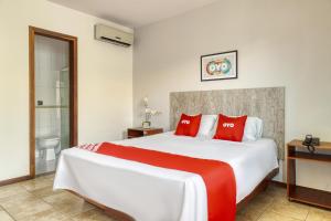 a bedroom with a large white bed with red pillows at OYO Pousada Maristella - Salvador in Salvador