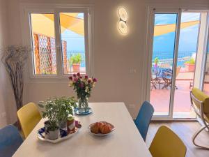 a dining room with a table with flowers and a balcony at Vista Mare Borgo Peri in Imperia
