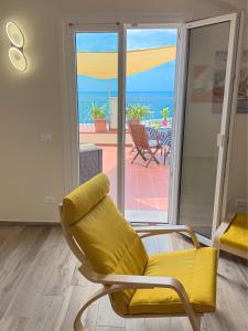 una silla amarilla en una habitación con vistas al océano en Vista Mare Borgo Peri, en Imperia