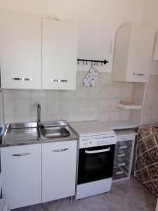a white kitchen with a sink and a stove at Casa sul mare in Procida