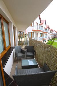 a balcony with chairs and tables on a building at Apartamenty Na Fali in Darłówko