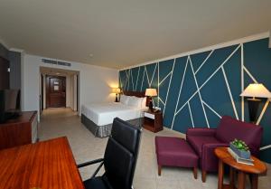 Crowne Plaza Panama, an IHG Hotel في مدينة باناما: غرفة في الفندق بسرير وكراسي ارجوانية