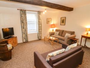 a living room with a couch and a tv at Dollar Ward House Basement in Cirencester