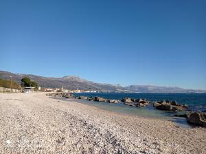a beach with rocks and water and mountains in the background at Barba Luka, near beach, beautiful views in Kaštela