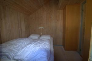 a bed in a room with a wooden wall at Hovborg Ferieby - Torpet 25 in Hovborg