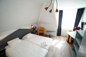 a small bedroom with a white bed and a desk at Hotel Brasserie Den Burg in Den Burg