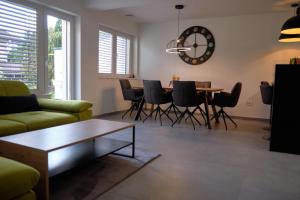 - un salon avec une table, des chaises et une horloge dans l'établissement Apartma La Casa, à Radovljica
