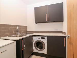 a kitchen with a washing machine and a sink at Treetops in Newton Poppleford