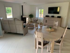 a living room with a table and chairs and a tv at BlackBerry Cottage - Maison de vacances - with WIFI in Lessay