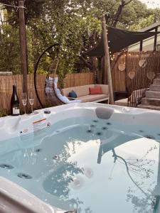 a jacuzzi tub in a backyard with a bottle of wine at Maison dans les Arbres, SPA, Tennis, Parking in Nîmes