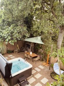 una bañera de hidromasaje en un patio trasero con una mesa y una tienda de campaña en Maison dans les Arbres, SPA, Tennis, Parking en Nimes