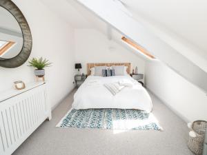 a white bedroom with a bed and a rug at The Nest in Dartmouth
