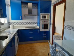 una cocina azul con armarios azules y fregadero en Bonito apartamento a 50 metros de la playa., en San Luis de Sabinillas