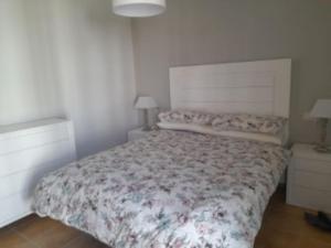 1 dormitorio con 1 cama con colcha de flores en Bonito apartamento a 50 metros de la playa., en San Luis de Sabinillas