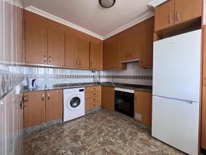 una cucina con armadi in legno, lavatrice e asciugatrice di Apartamentos Mar Menor a Los Alcázares