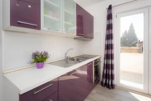 a kitchen with purple cabinets and a sink and a window at Apartment More in Blace