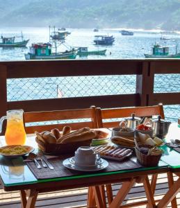 a table with food and a view of the water at Pousada Convés - Ilha Grande in Praia de Araçatiba +58 photos