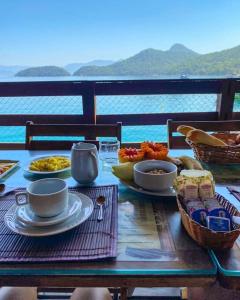 - une table avec des assiettes de nourriture sur le balcon dans l'établissement Pousada Convés - Ilha Grande, à Praia de Araçatiba