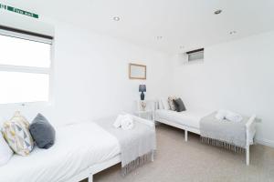 a white room with two beds and a window at Causeway Bay in Marazion