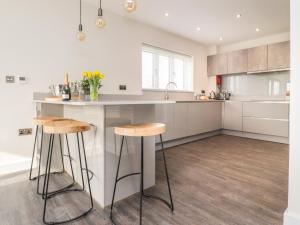 a kitchen with a counter and two stools at Laundry Cottage in Milnthorpe