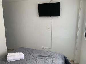 1 dormitorio con 1 cama y TV de pantalla plana en la pared en Apartaestudio de la 80 por el Titán Plaza 101 en Bogotá