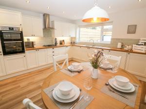 uma cozinha com uma mesa de madeira e uma sala de jantar em 2 Rhoslyn em Caernarfon