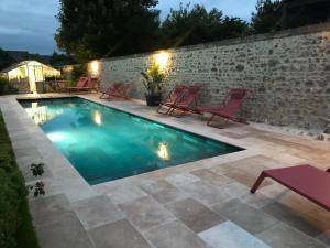 a swimming pool with chairs and a brick wall at Clos Saint Nicolas in Neauphle-le-Château