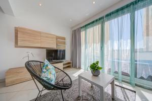 - un salon avec une chaise, une table et une grande fenêtre dans l'établissement Sapphire Residences - Apartments & Penthouse In Central Sliema By Shortletsmalta, à Sliema