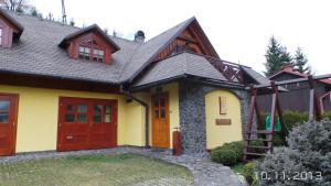 a yellow house with red doors and a gray roof at Chaty Helena in Vyšná Boca