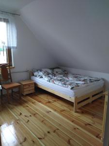 Schlafzimmer mit einem Bett und Holzboden in der Unterkunft dom drewniany pod lasem in Zatory