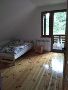 Schlafzimmer mit einem Bett und Holzboden in der Unterkunft dom drewniany pod lasem in Zatory