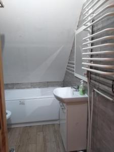 ein Badezimmer mit einem Waschbecken, einer Badewanne und einem WC in der Unterkunft dom drewniany pod lasem in Zatory