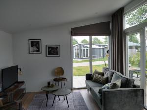 a living room with a couch and a tv at Lathumlodge met parkvoorzieningen in Lathum