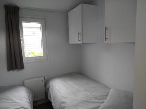 2 camas en una habitación con ventana y armarios blancos en Lathumlodge met parkvoorzieningen en Lathum