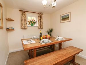 a dining room with a wooden table and a bottle of wine at Hedgehog Cottage in Minehead