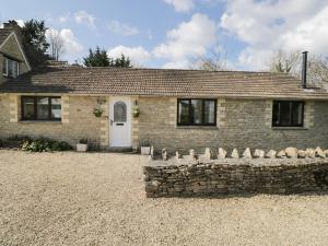 a brick house with a stone wall in front of it at Orchard House Cottage in Malmesbury