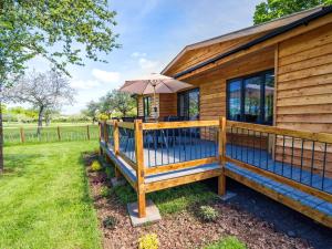 ein Holzhaus mit einer Terrasse mit einem Sonnenschirm in der Unterkunft Top Style Orchard in Worcester