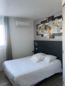 1 dormitorio con 1 cama con sábanas blancas y flores en la pared en L'Hôtel du Marais Romilly Centre en Romilly-sur-Seine