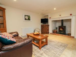 a living room with a couch and a table and a fireplace at Barn Owl Cottage in Minehead