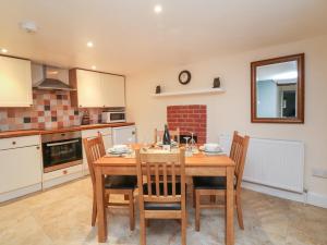 a kitchen with a wooden table and chairs at Barn Owl Cottage in Minehead +18 photos