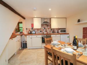 a kitchen with a table and chairs and a kitchen with white cabinets at Barn Owl Cottage in Minehead