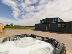 a hot tub in a backyard with a black house at Phoenix House in Castlemorton