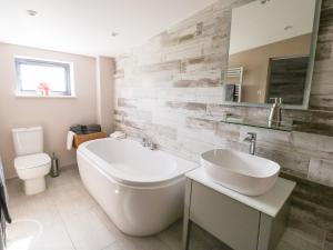 a bathroom with a tub and a sink and a toilet at Phoenix House in Castlemorton +52 photos