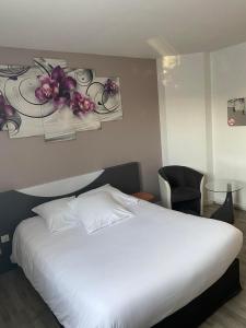een slaapkamer met een wit bed en bloemen aan de muur bij L'Hôtel du Marais Romilly Centre in Romilly-sur-Seine