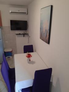 a white table with two blue chairs and a television at Apartments Knežić in Igrane